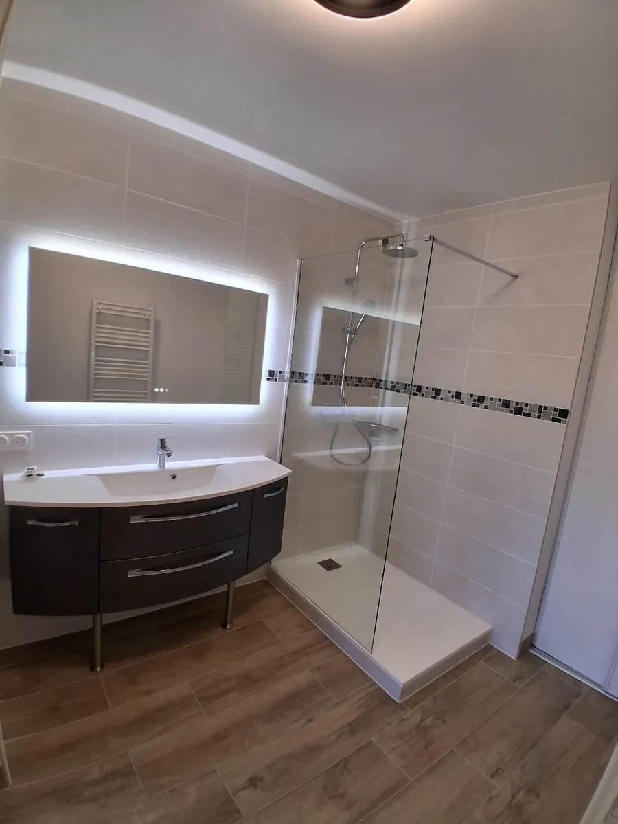 Salle d'eau rénovée avec douche italienne, meuble vasque gris et miroir rétroéclairé, en Essonne